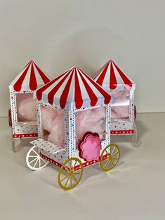 a toy horse drawn carriage with two red and white umbrellas