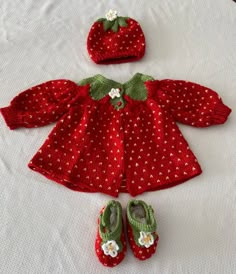 a red knitted doll outfit with matching shoes and hat on a white tablecloth