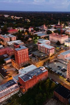 an aerial view of a city at night with cars parked in the lot and buildings lit up