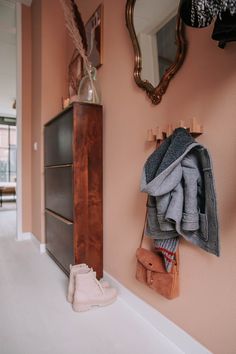 there is a coat hanging on the wall next to a shoe rack with shoes in it