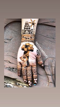 a woman's hand painted with hennap and designs on it, sitting on top of a rock