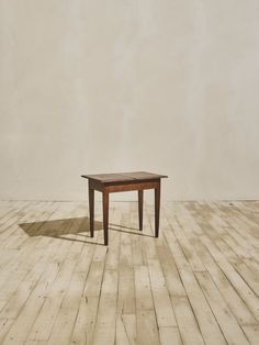 a small wooden table sitting on top of a hard wood floor next to a wall