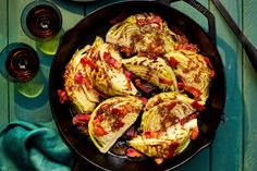 an iron skillet filled with cooked cabbages and bacon on a blue wooden table