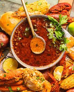 a bowl filled with chili sauce surrounded by corn, limes and other food items