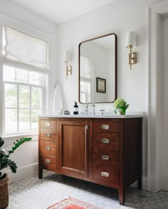 a bathroom with a sink, mirror and potted plant in the window sill