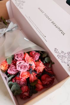 a bouquet of pink and red roses in a box