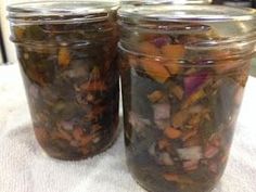 two jars filled with food sitting on top of a white tablecloth covered table cloth