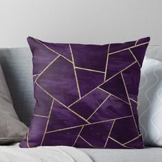 a purple throw pillow with gold lines on the front and back, sitting on a couch