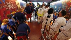 a group of people standing in a hallway next to a wall with pictures on it