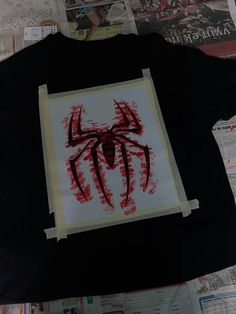 a spider - man t - shirt is being displayed on top of newspaper clippings