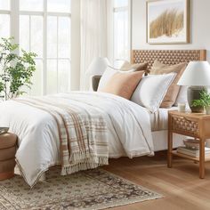 a bed sitting in a bedroom next to a window with lots of pillows on top of it