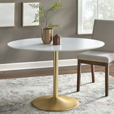 a white and gold dining table with two chairs in front of the table, next to a potted plant