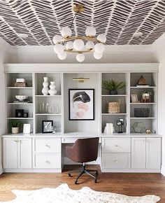 an office with white bookcases, shelves and a cowhide rug on the floor