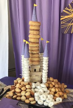 a castle made out of doughnuts sitting on top of a purple table cloth