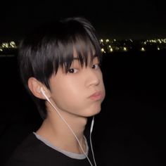 a young man with earphones on his ears looking at the camera in the dark