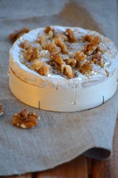 a wooden table topped with a white cake covered in walnuts on top of a piece of cloth