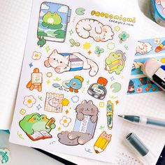 an open notebook with various stickers on it and markers next to it, along with pens