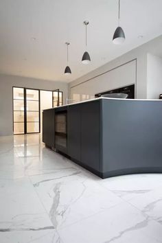 a kitchen with marble flooring and black cabinets in the center, along with hanging lights