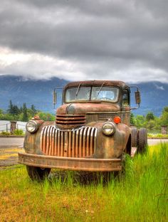 an old truck sitting in the middle of a field