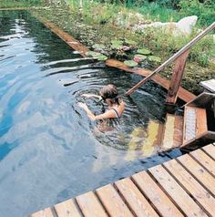 a person swimming in a body of water next to a wooden dock with steps leading up to it