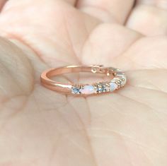 a woman's hand is holding a ring with opals on it and three stones in the middle