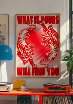 a red and white poster on the wall above a desk with record player, speakers and lamp