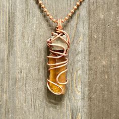 Handcrafted natural citrine and cubic pyrite necklace, intricately wrapped in bare copper wire. This one-of-a-kind piece merges the vibrant energy of citrine, known as the "Stone of Abundance," with the grounding and protective qualities of pyrite. The raw beauty of both stones is beautifully complemented by the rustic charm of copper, creating a unique, high-energy talisman for daily wear. This necklace is more than just an accessory; it's a powerful piece of metaphysical jewelry designed to attract abundance and protect your energy field. *Handmade with natural citrine and cubic pyrite stones *Wrapped in heavy gauge bare copper wire *Chain length: 22" *Pendant size: 2.2" *Copper ball chain necklace  *Perfect for daily wear or as a unique gift for someone special Metaphysical Properties: Amber Copper Necklace For Healing, Healing Crystal Necklaces With Gemstone And Copper, Adjustable Citrine Necklaces For Healing, Wire Wrapped Citrine Jewelry For Healing, Citrine Wire Wrapped Jewelry For Healing, Gold Copper Pendant Crystal Necklace, Bohemian Wire Wrapped Citrine Jewelry, Bohemian Citrine Wire Wrapped Jewelry, Spiritual Copper Necklace With Gemstone