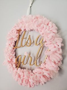 a pink wreath with the words it's a girl written in gold on it