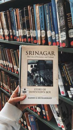 a person holding up a book in front of a bookshelf filled with books