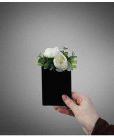 a person holding a black box with white flowers in it