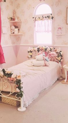 a bedroom decorated in pink and white with flowers on the bedspread, windows, and curtains