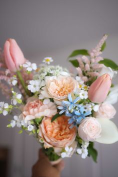 a person holding a bouquet of flowers in their hand with white and pink flowers on it