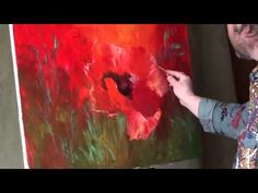 a man is painting a red flower on an easel