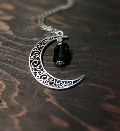 This beautiful crescent moon necklace will inspire all your moonlit nights. This made to order necklace features silver toned metals and a black tourmaline gemstone. product details Silver tone metals Choose your chain length Black tourmaline gemstone; Each piece is unique. The stone varies but is roughly 1/4 inch long or smaller. Each stone is natural and unique. Metaphysical properties of black tourmaline: One of the only stones that heals and protects on all levels, physical, mental, spiritua Gothic Crescent Moon Charm Jewelry, Gothic Moon Charm Pendant Necklace, Gothic Necklaces With Moon Charm Pendant, Gothic Pendant Necklaces With Moon Charm, Gothic Moon Charm Pendant Necklaces, Gothic Adjustable Necklace With Moon Charm, Gothic Crescent Moon Phase Jewelry, Gothic Style Moon Charm Necklace Gift, Gothic Moon Charm Necklace As Gift