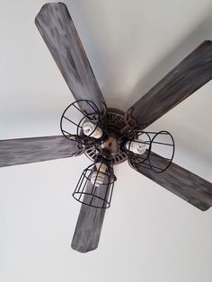 a ceiling fan that is made out of wood and metal caged with light bulbs