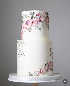 a three layer white cake with pink flowers on it