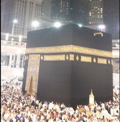 the ka'bah is surrounded by people in front of tall buildings at night