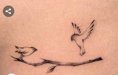 a small tattoo on the back of a woman's stomach with two birds flying over it