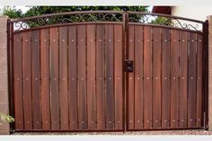 a wooden gate with wrought iron bars on the top and bottom, in front of a house