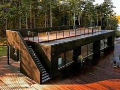 a house that is sitting on top of a wooden deck next to water and trees