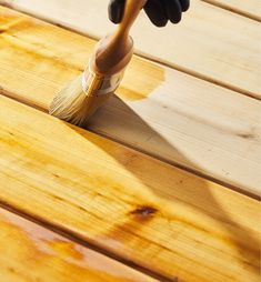 a person holding a paint brush on top of a wooden decking planked floor