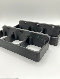 two black plastic trays sitting on top of a white table next to each other