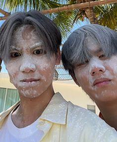 two people standing next to each other covered in white powder and coconut trees behind them