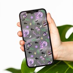 a person holding an iphone case with skulls and stars on it in front of a plant