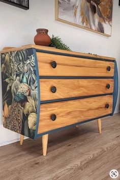 a wooden dresser with peacocks painted on the front and side drawers, sitting in a living room