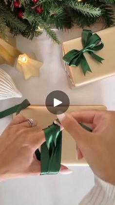 someone wrapping presents under the christmas tree with green ribbon and bows on it, while another person places them in their hands