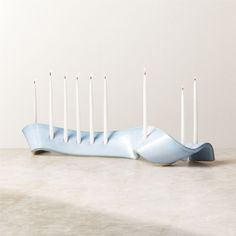 a blue candle holder sitting on top of a table with five white candles in it