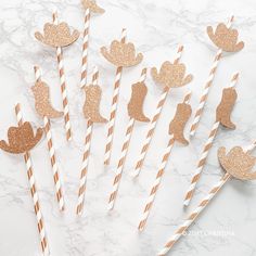 paper straws decorated with gold glitter and mermaid silhouettes are on a marble surface