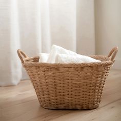 a wicker basket with white towels in it on the floor next to a window