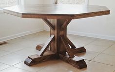 a wooden table sitting in the middle of a room with tile flooring and white walls